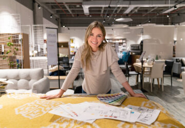 A female designer smiles while looking over plans for a project.