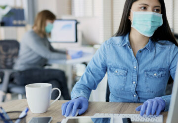 Woman in protective gloves and mask in the office